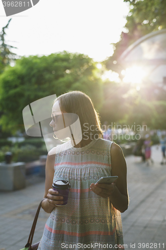 Image of the woman with the phone drinking coffee in the Park