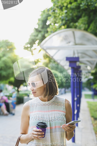 Image of the woman with the phone drinking coffee in the Park