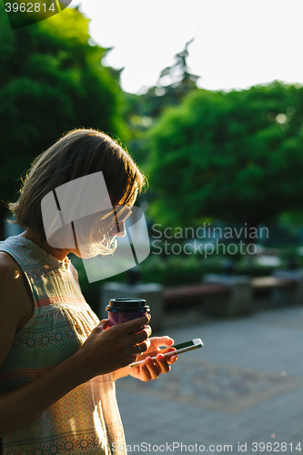 Image of woman drinking coffee and looking at phone