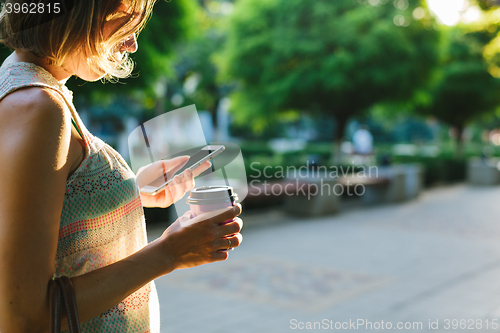 Image of woman drinking coffee and looking at phone