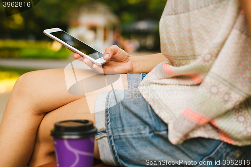 Image of woman drinking coffee and looking at phone