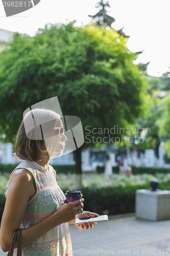 Image of woman drinking coffee and looking at phone