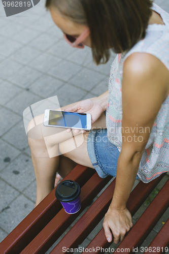 Image of woman drinking coffee and looking at phone