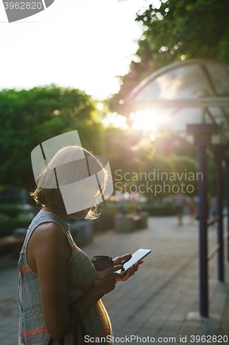 Image of woman drinking coffee and looking at phone