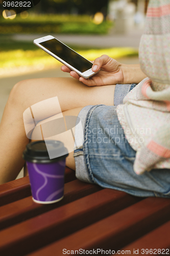 Image of woman drinking coffee and looking at phone