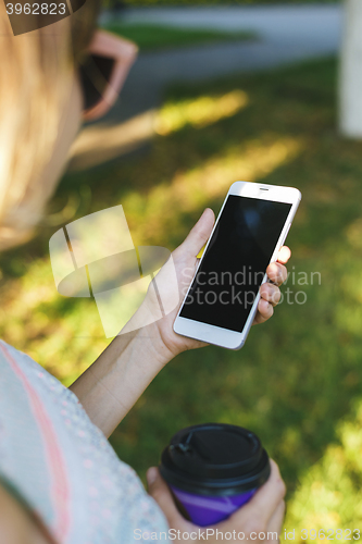 Image of woman drinking coffee and looking at phone