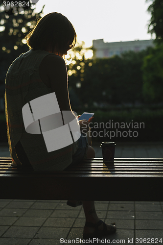 Image of woman drinking coffee and looking at phone