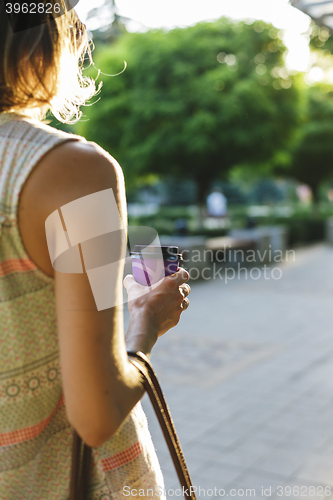 Image of woman walks down the street and drinks coffee