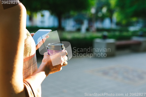 Image of woman drinking coffee and looking at phone