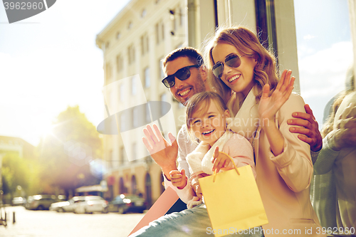 Image of happy family with child and shopping bags in city