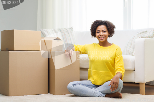 Image of happy african woman with cardboard boxes at home