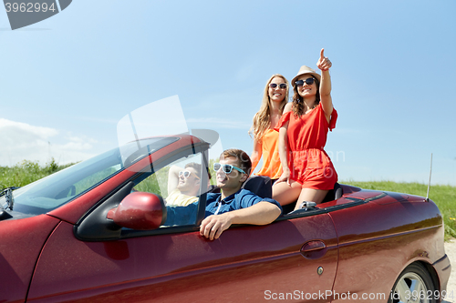 Image of happy friends driving in cabriolet car at country