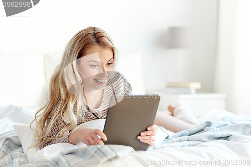 Image of happy young woman with tablet pc in bed at home