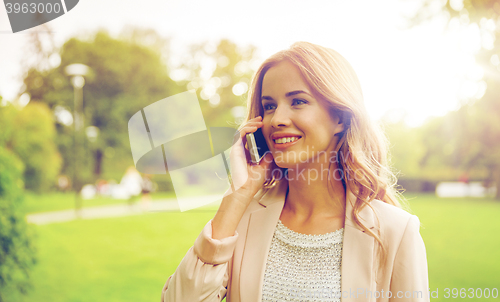 Image of smiling young woman calling on smartphone outdoors