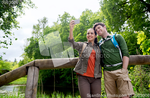 Image of couple with backpacks taking selfie by smartphone