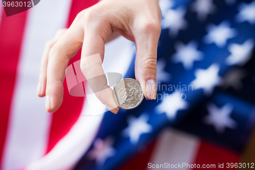 Image of close up of hands with coins over american flag