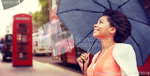 Image of happy african woman with umbrella in london city