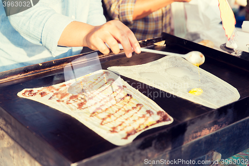 Image of close up of cook frying pancakes at street market