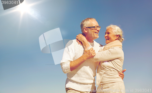 Image of happy senior couple hugging outdoors