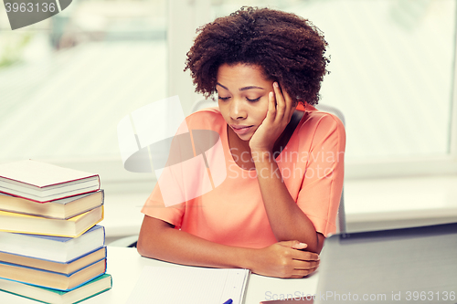 Image of bored african american woman doing homework home