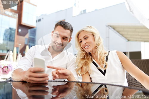 Image of happy couple with smatphone at restaurant terrace