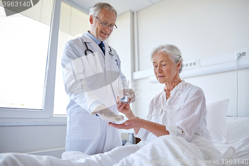 Image of doctor giving medicine to senior woman at hospital