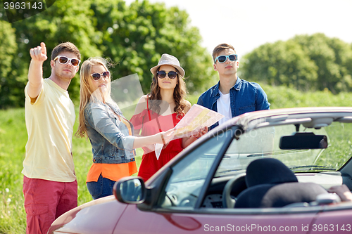 Image of happy friends driving in cabriolet car