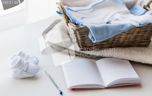 Image of close up of baby clothes for newborn and notebook