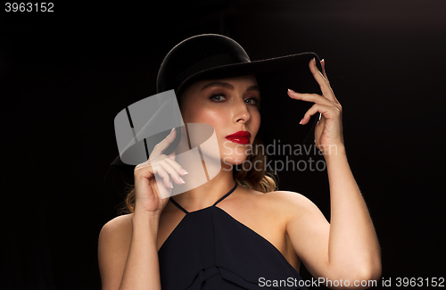 Image of beautiful woman in black hat over dark background