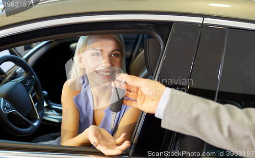 Image of happy woman getting car key in auto show or salon