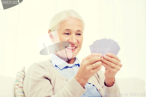 Image of happy senior woman playing cards at home