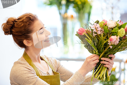 Image of smiling florist woman making bunch at flower shop