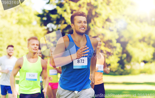 Image of happy young sportsmen racing wit badge numbers