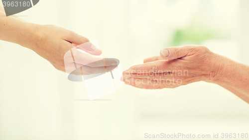 Image of close up of senior and young woman hands