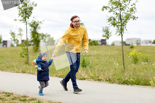 Image of happy father and son with pinwheel toy outdoors