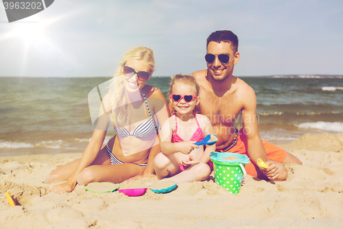 Image of happy family playing with sand toys on beach