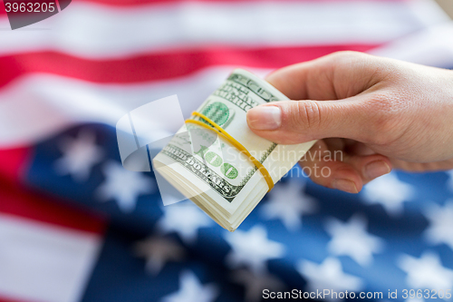 Image of close up of hand with money over american flag