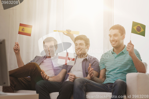 Image of happy male friends with flags and vuvuzela