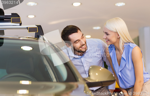 Image of happy couple buying car in auto show or salon