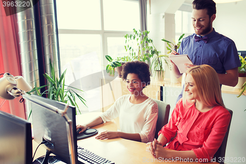 Image of happy creative team with computer in office
