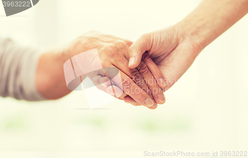 Image of close up of senior and young woman holding hands