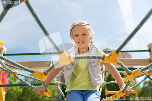 Image of happy little girl climbing on children playground