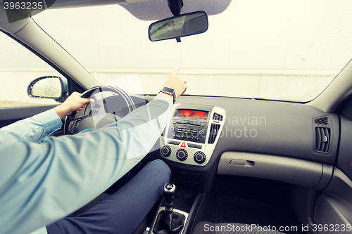 Image of close up of man driving car and pointing finger