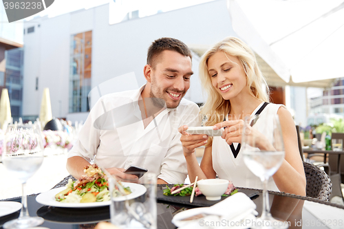 Image of happy couple with smatphone at restaurant terrace