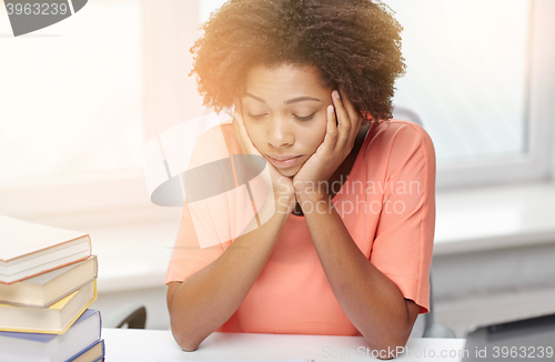 Image of bored african american woman doing homework home