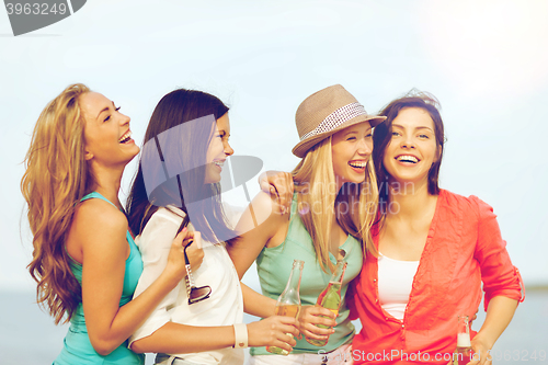Image of smiling girls with drinks on the beach