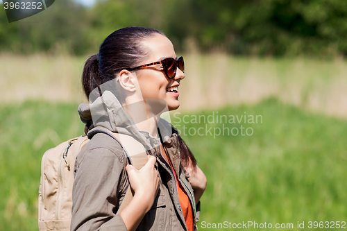 Image of happy young woman with backpack hiking outdoors