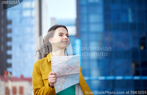 Image of happy young woman traveling with map in city