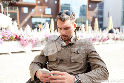 Image of young man texting on smartphone at city terrace