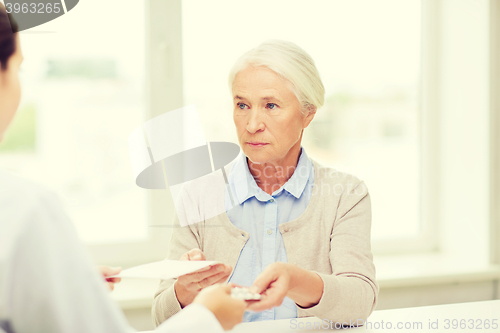 Image of doctor giving prescription and drug to woman 